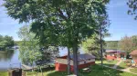 A view of three of the cabins at Twin Bay Resort on the lake showing trees, picnic tables, cabins, and the lake.